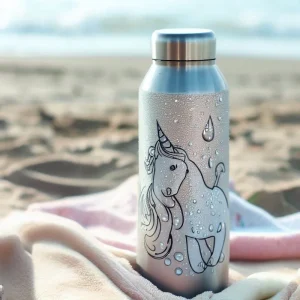 Una botella térmica de unicornios sobre una toalla de playa